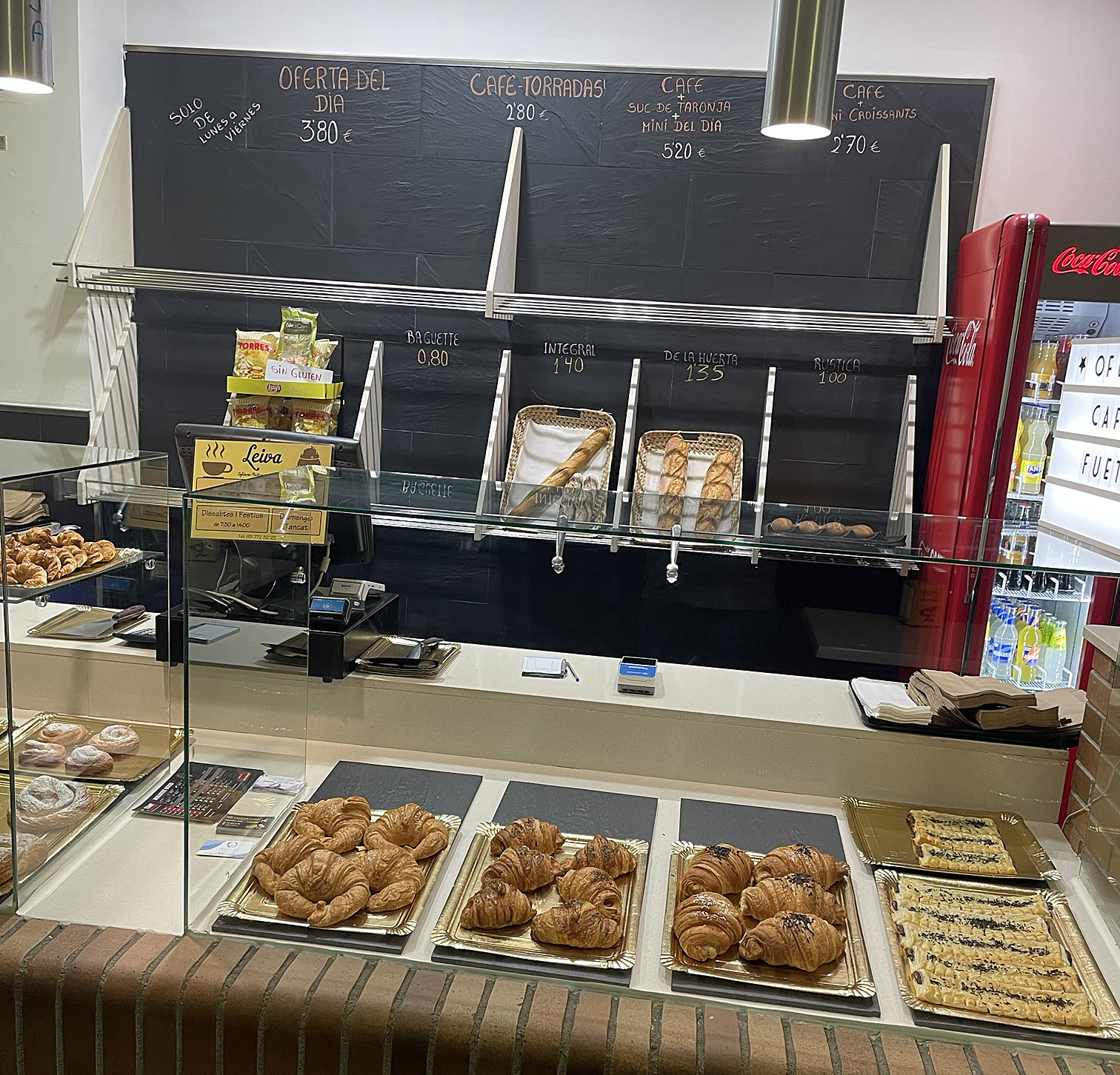 Vitrina con croissants y bollería, y la pizarra con las ofertas y el pan